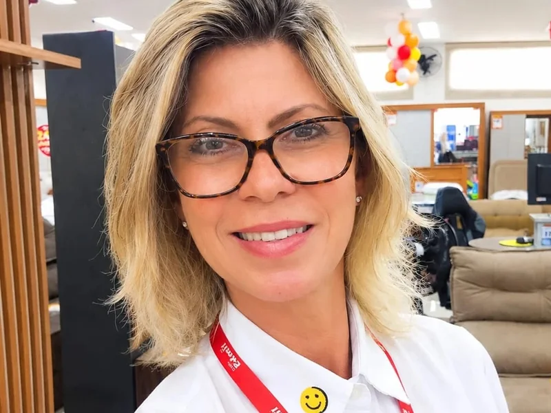 Adriana sorrindo, de uniforme, dentro da Lojas Edmil